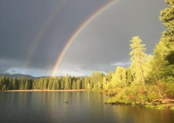 A double rainbow over a lake with cloudy skies
