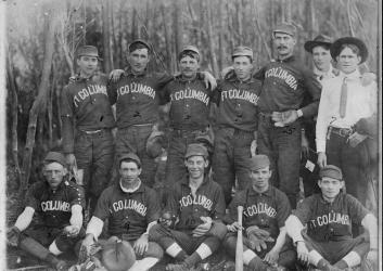 A black and white photograph of baseball players sitting in rows in their uniforms.