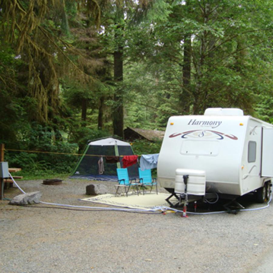 A camper along with foldable chairs in a campsite.